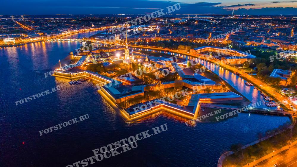 Фотография демонстрирует великолепный ночной вид на Петропавловскую крепость в Санкт-Петербурге, сделанный с высоты птичьего полета. Изображение отлично подойдет для путеводителей, культурно-исторических изданий, а также для рекламных и образовательных проектов, желающих подчеркнуть уникальность и красоту архитектурного наследия города.